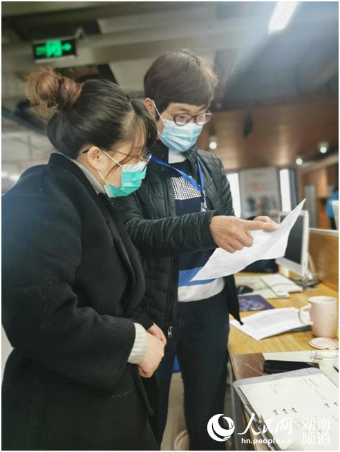 駐企聯絡員查看企業員工體溫監測統計表，逐一核對名單。謝麗娜 攝
