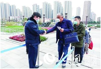 工作人員在對前來辦事的市民進行體溫檢測。馬文章 攝