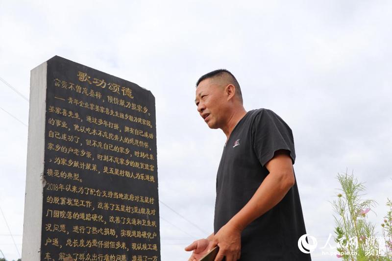 五星村村支書李剛烈站在記有鄉賢姜家喜先進事跡的碑前。肖琳 攝