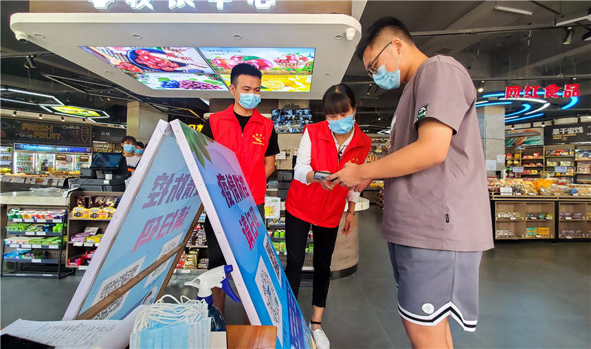 8月10日，在湖南省常寧市一水果超市，志願者引導市民掃描健康碼、行程碼。周秀魚春攝