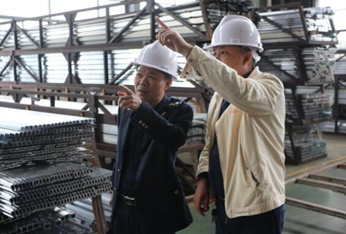 汨羅市稅務局負責人張峰(左)在振升鋁業科技有限公司調研。受訪單位供圖