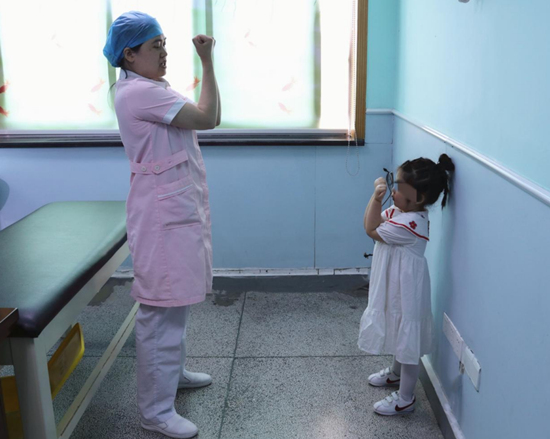 湖南省儿童医院呼吸内科主管护师钟丽娜（左一）教檬檬做康复操。受访单位供图