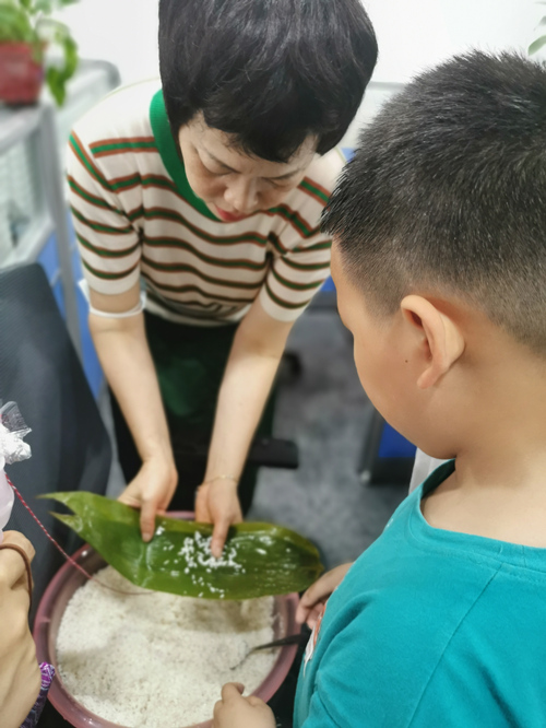 家长教孩子包粽子。受访单位供图