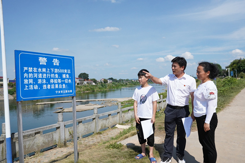 寧鄉市壩塘鎮團山學校校長、黨員黃俊杰（左二）正在溈江立新壩段宣傳防溺水知識。受訪單位供圖