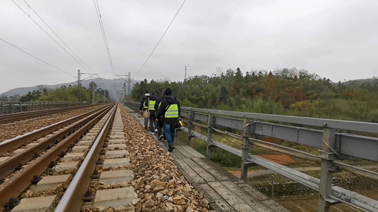 吴盛和队友行走在铁路高架桥上。受访单位供图