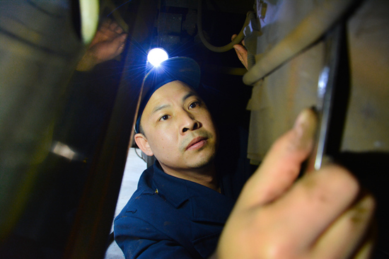 行安组涂荣俊在机车走行部进行轴报线路检修。受访单位供图