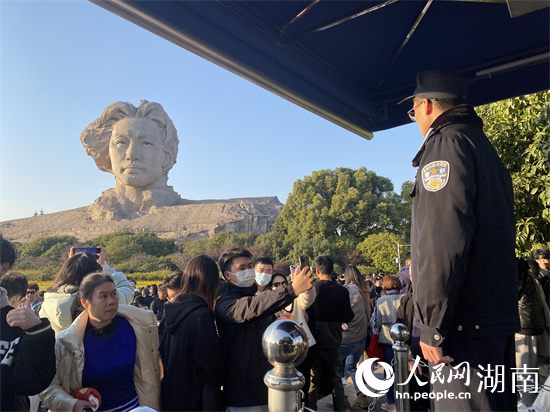 警务人员在毛泽东青年艺术雕像前站岗执勤，巡视周边治安状况。 人民网 向宇摄