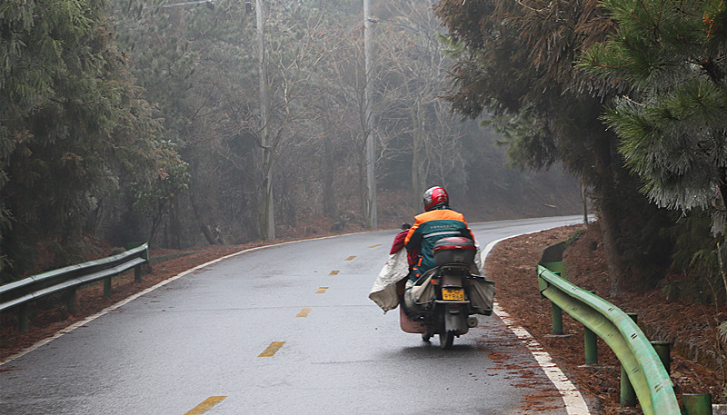 老楊駕駛摩托車在送件的路上。李無我攝