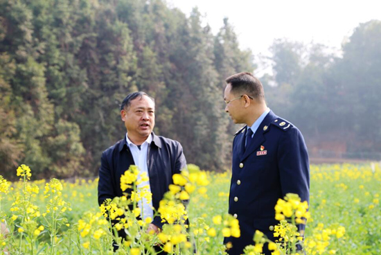 全国人大代表、“农民科学家”沈昌健（左）在油菜基地与税务干部交流税费政策。受访单位供图