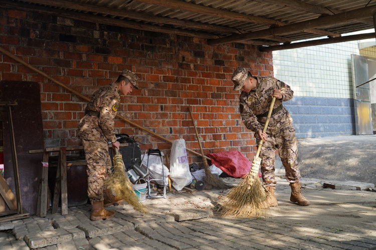 武警望城中队官兵帮助驻地附近孤寡老人打扫房屋。武警长沙支队供图
