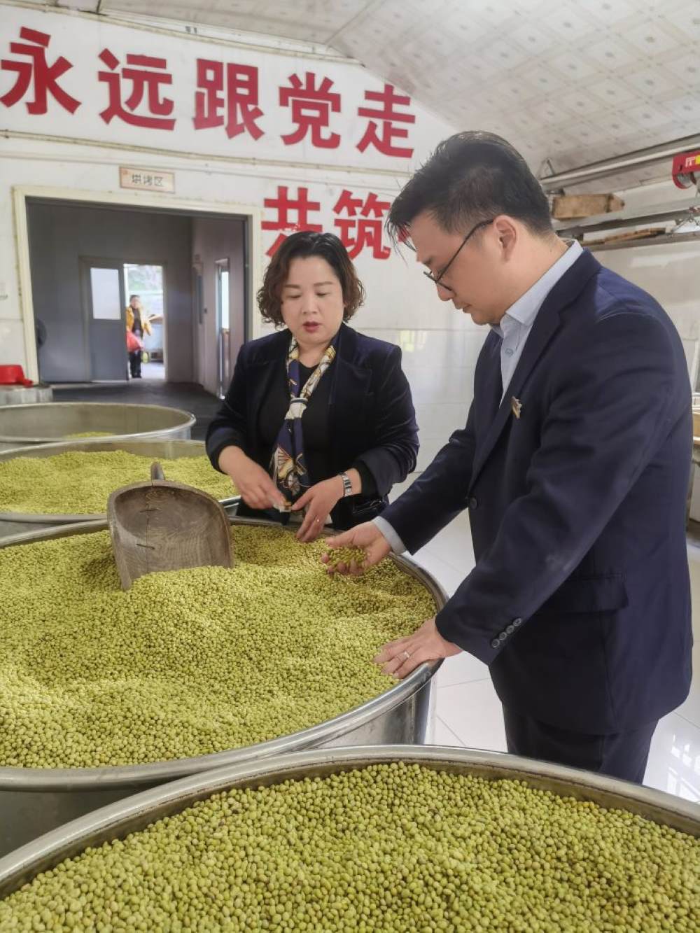 矮寨支行行长在石清香作坊查看豆子。单位供图