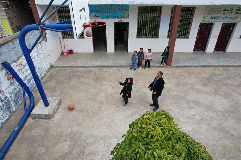 赵书万带着孩子在操场上联系篮球。人民网记者 李芳森摄