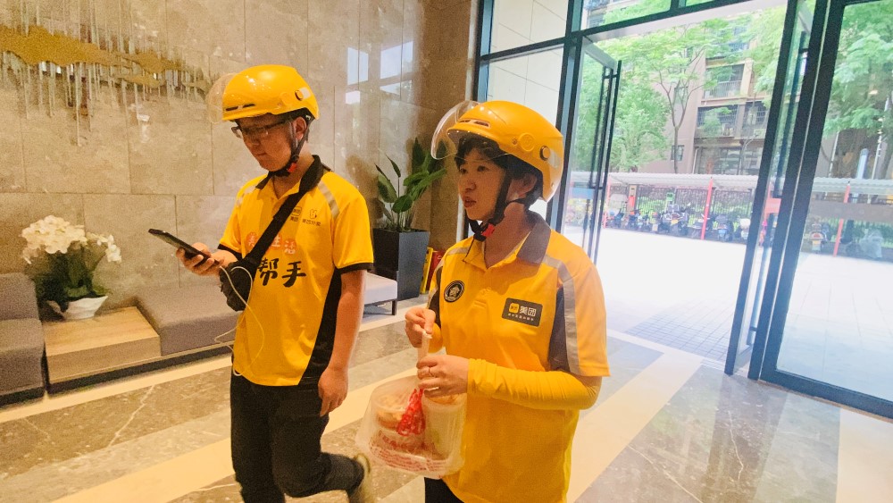 星沙街道党工委委员、组织委员周曦（右）和“师傅”黄康一起完成送餐任务。刘思源摄