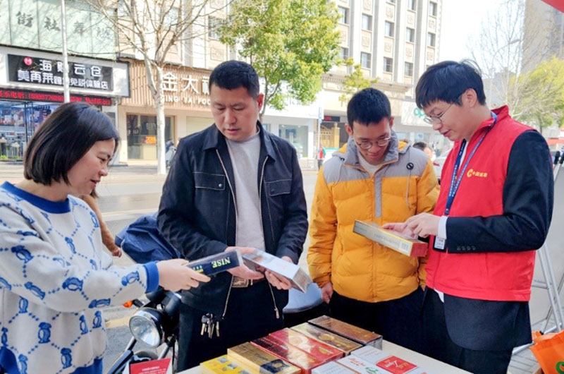 志愿者为群众讲解真假烟识别。向丽摄