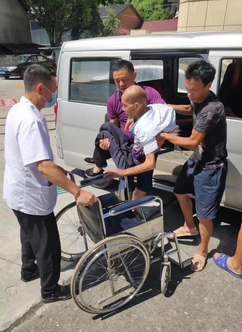 覃道康將老人從車上小心抱下車。受訪單位供圖
