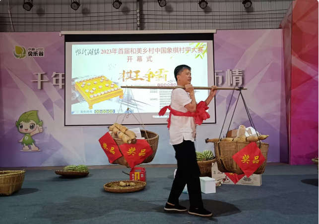 “镇棋王”张一一身披大红花肩挑两箩筐当地农特产品奖品。主办方供图
