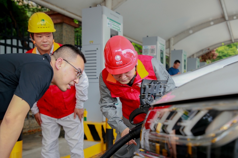 國網岳陽供電公司東方紅（電駱駝）共產黨員服務隊隊員指導客戶使用電動汽車充電樁。劉天攝