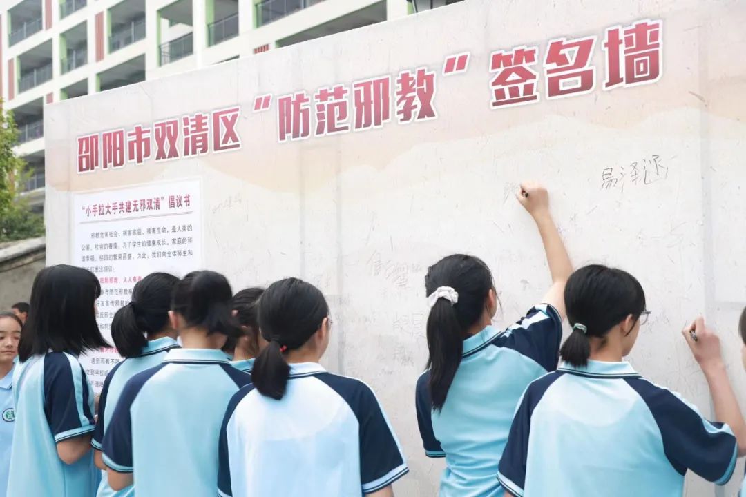 学生们在“防范邪教” 签名墙上签名。单位供图