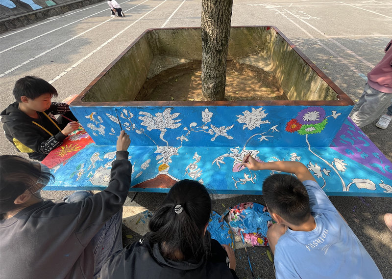 学生在校园内的树坛上绘画。光明小学供图