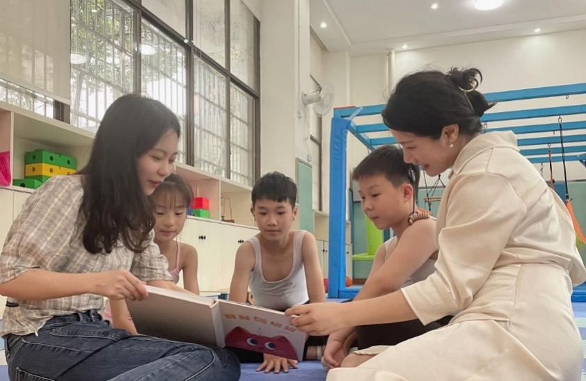 杨雅儒（左）在特殊教育学校为听障儿童们展示绘本《蜗蜗与酥酥》。单位供图
