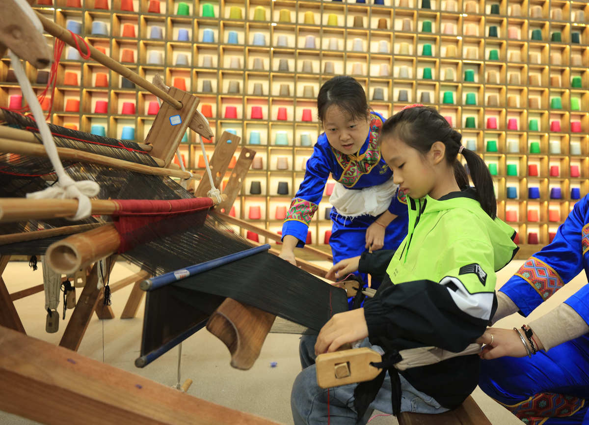 10月5日，来自深圳南山外国语学校（集团）科苑小学的学生在张家界市武陵源区乖幺妹土家族织锦基地学习体验土家族织锦制作技艺。吴勇兵摄