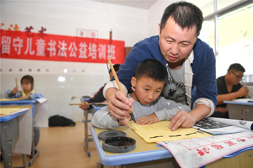 老师教学生写毛笔字。傅聪摄