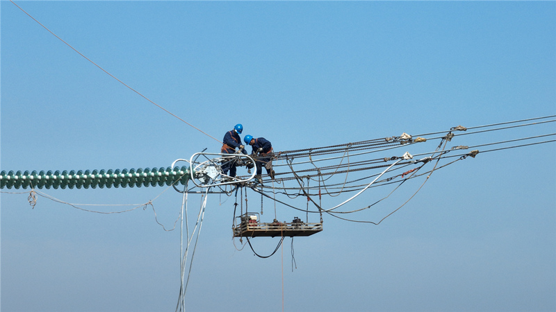 国网湖南送变电公司员工在益阳东500千伏变电站配套线路工程D18号施工现场进行紧挂线工作，全力推进工程建设。受访单位供图