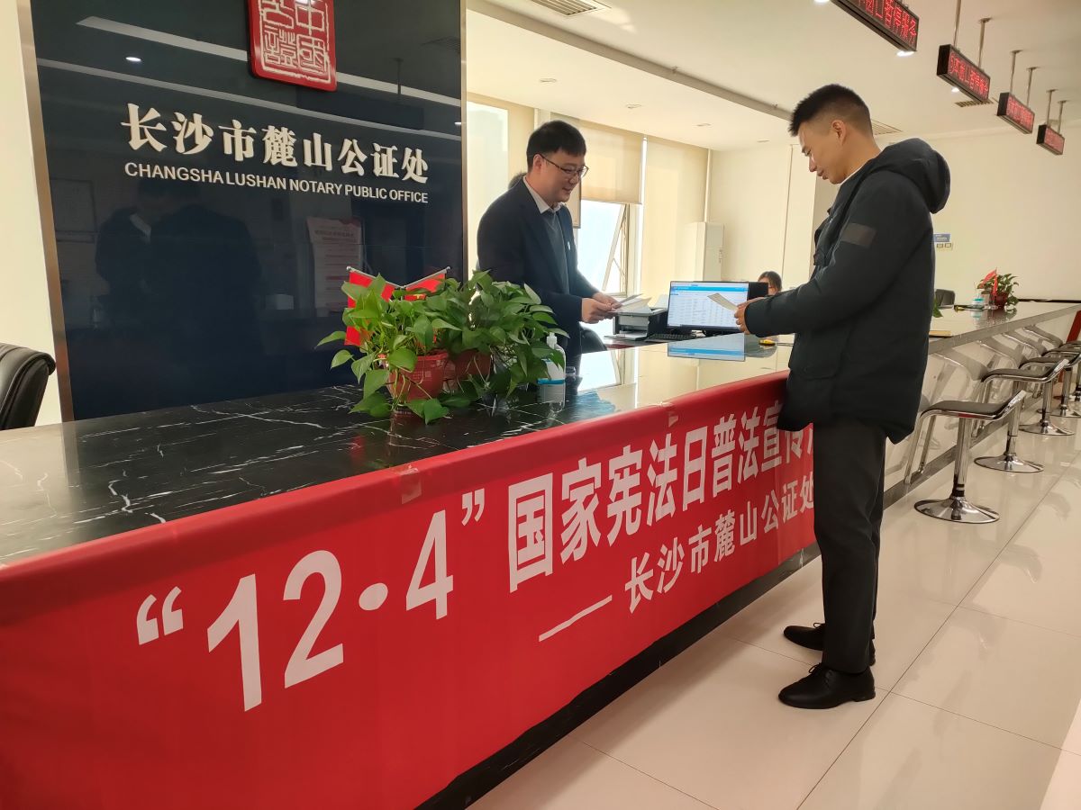 公証員向前來銀行辦理金融業務的當事人發放了《中華人民共和國憲法》宣傳手冊等其它普法宣傳資料。章朝輝攝