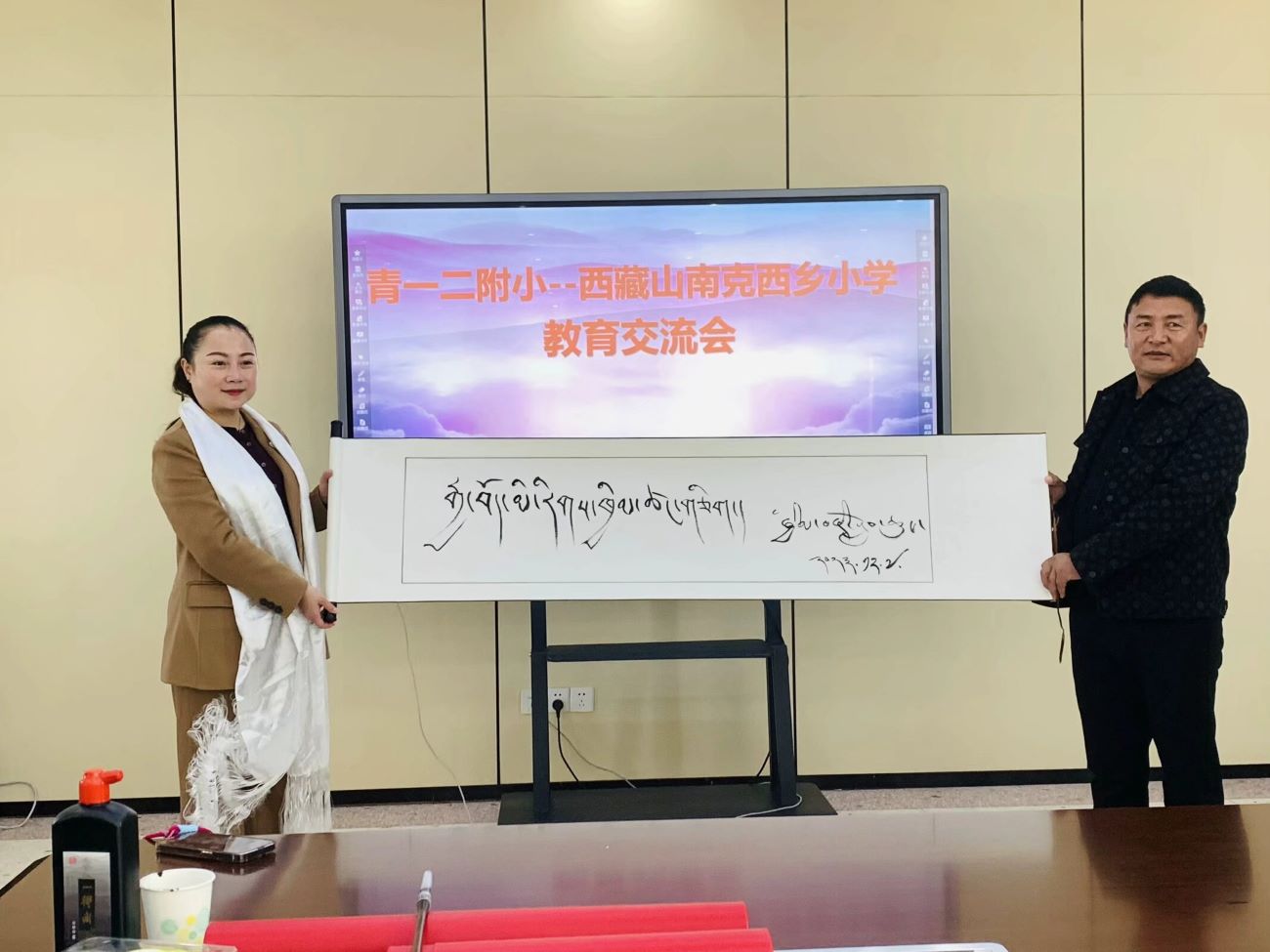 旦增久米校長現場寫下“漢藏一家親”的藏文書法，贈送給青一二附小。單位供圖