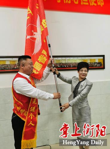 市委宣传部副部长、文明办主任谭春兰为志愿服务队授旗（单位供图）
