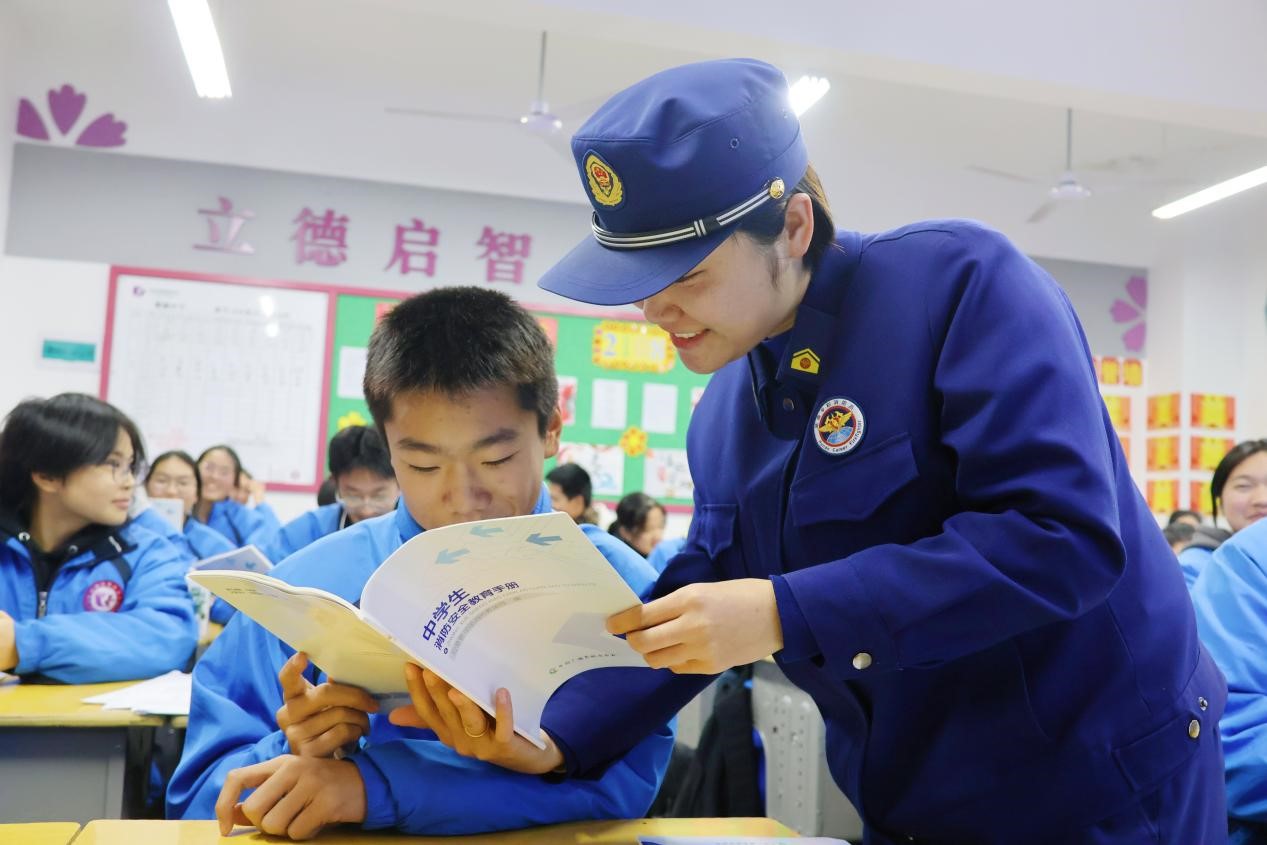 消防宣传员在为学生介绍《中学生消防安全教育手册》（单位供图）