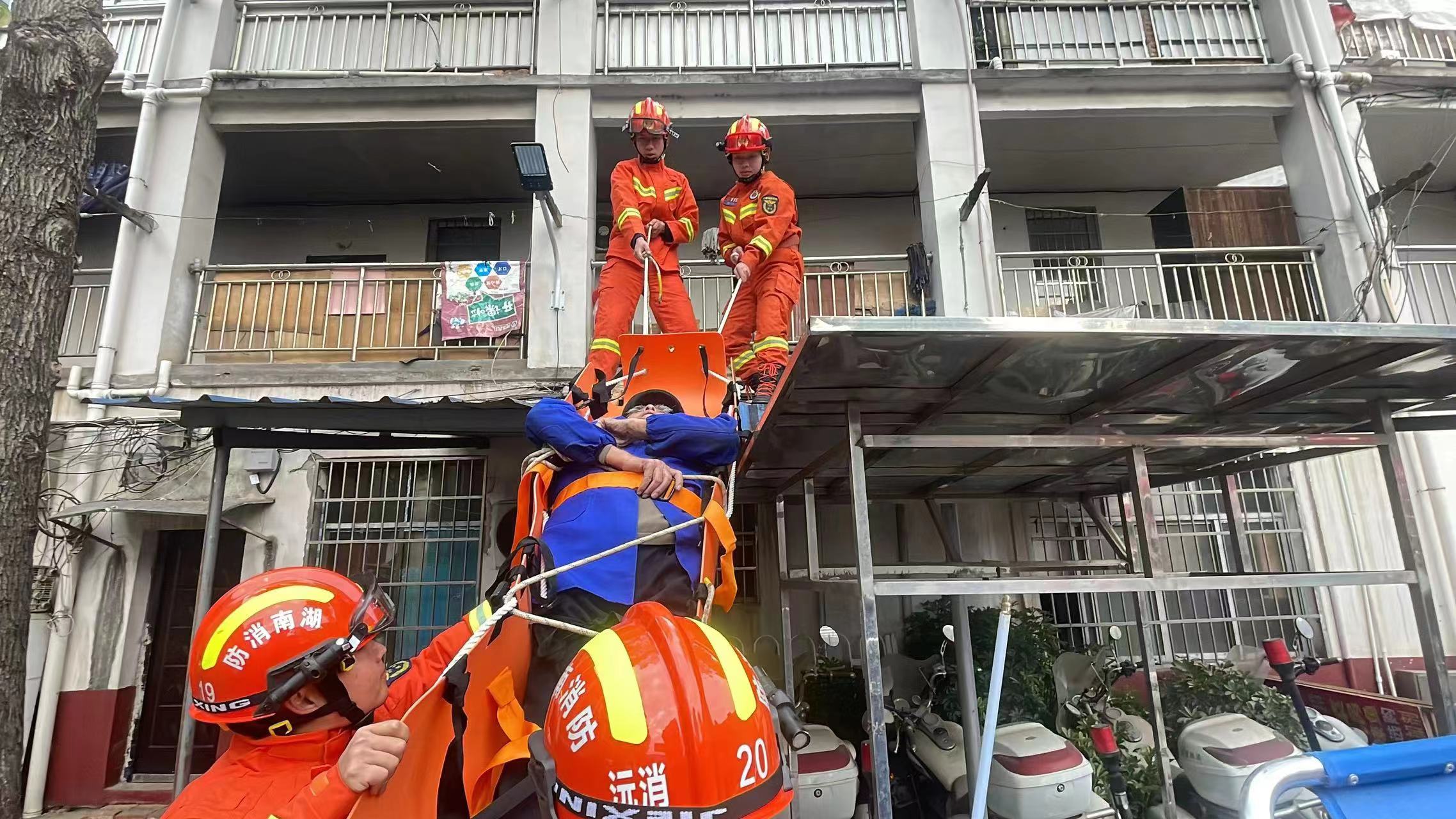 消防救援人員正在將老人從雨棚上轉移至地面安全區域（單位供圖）