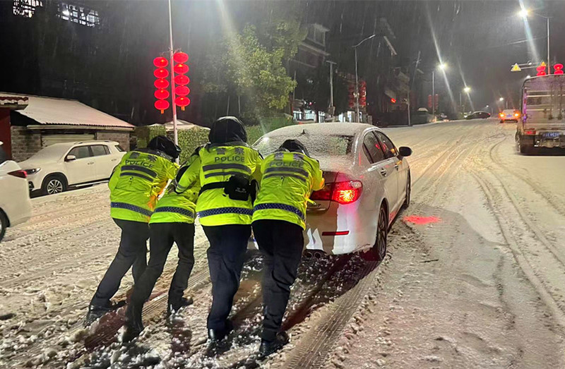 交警合力推動困在雪地的私家車。湘西公安供圖