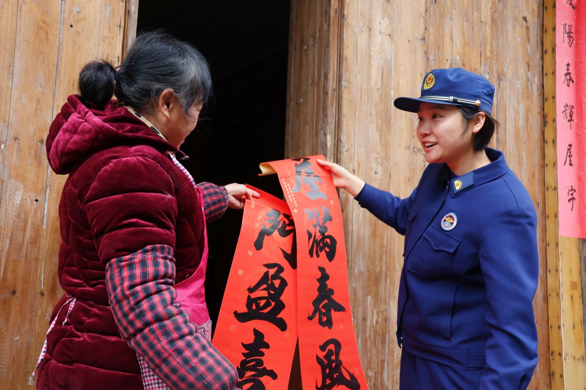消防宣传员邓文婕为村民送上新春对联（单位供图）