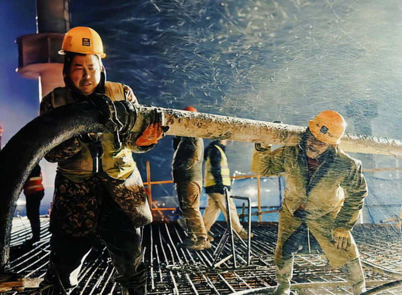 泥工张久云（左前）、张胜波（右前）正和班组其他工友连夜进行泵管拼装。受访单位供图