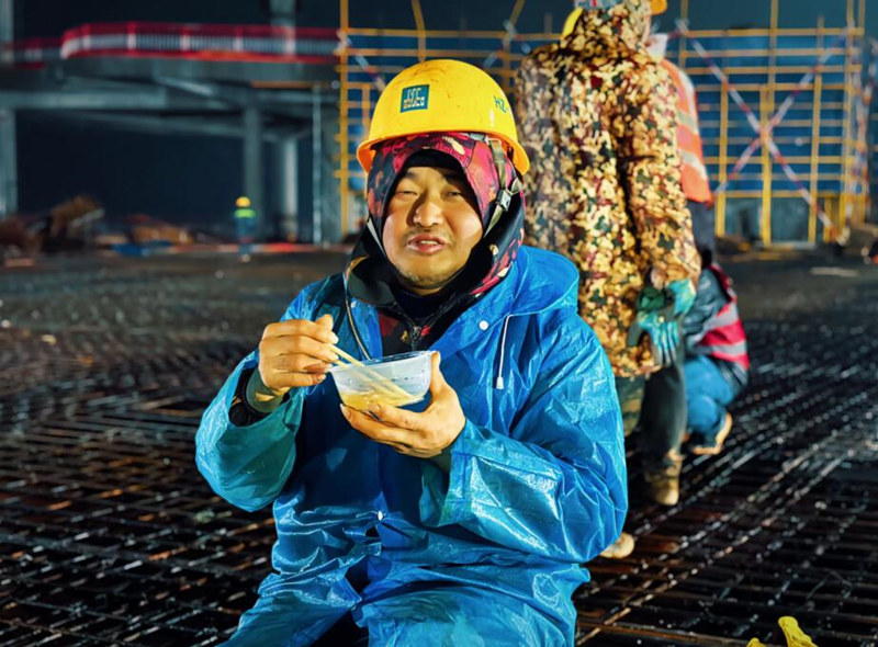 钢筋师傅宋朝晖在工作间隙吃起热乎乎的饺子。受访单位供图