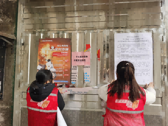 圖為消防志願者張貼電動自行車安全提示海報（單位供圖）