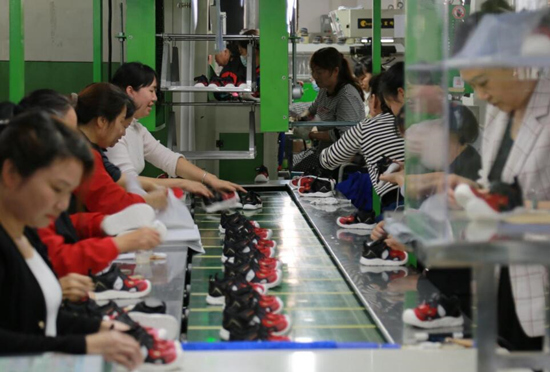 宁远高新区一鞋企车间，工人在赶制订单产品。郑明辉摄
