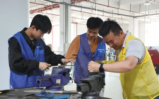 新田县职业中专机械加工专业学生在老师指导下完成机器调试、材料打磨等工序。肖亚湘摄