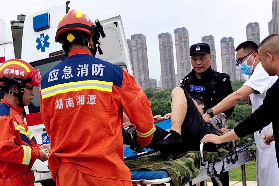 图为消防救援人员护送伤者上救护车（单位供图）