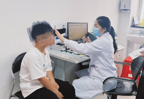 主任覃银燕为儿童患者进行眼部检查。受访单位供图