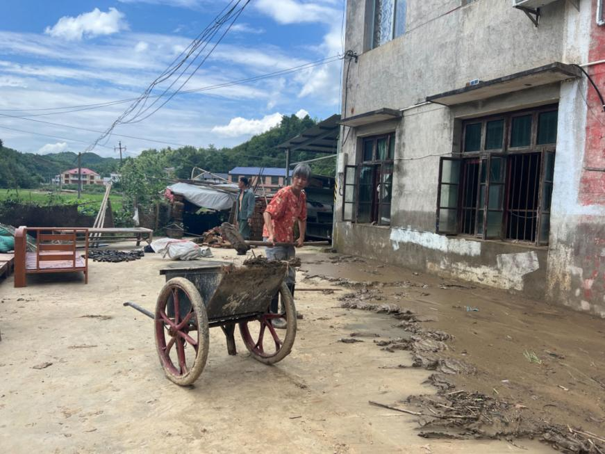 平江县梅仙镇三里村受灾民众在清理家附近的淤泥。杨迅摄