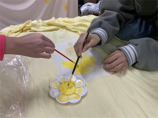 许少玲指导学生在布料上绘制服饰纹样。学校供图