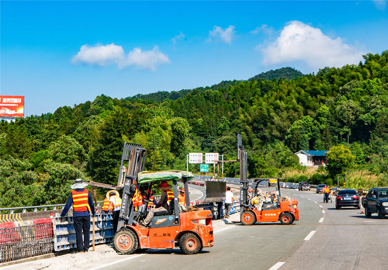 工程建设者们冒着酷暑抢抓工程进度,进行高速公路中央分隔带护栏提升改造工程施工。田文国摄