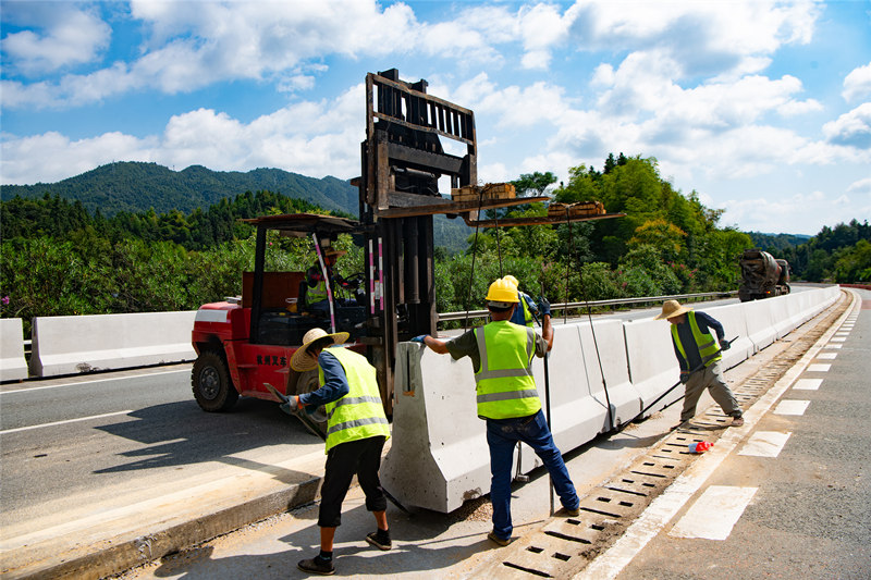 工程建设者们冒着酷暑抢抓工程进度，进行高速公路中央分隔带护栏提升改造工程施工。田文国摄