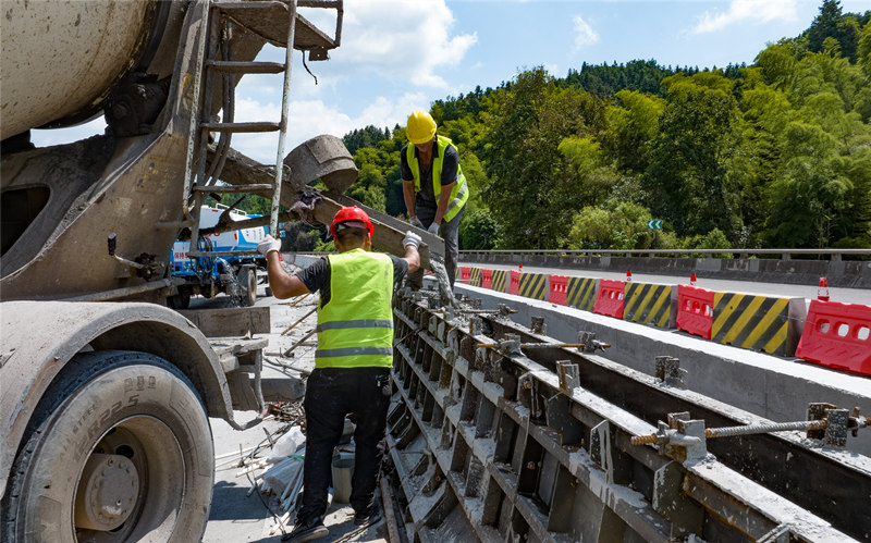 工程建设者们冒着酷暑抢抓工程进度，进行高速公路中央分隔带护栏提升改造工程施工。田文国摄