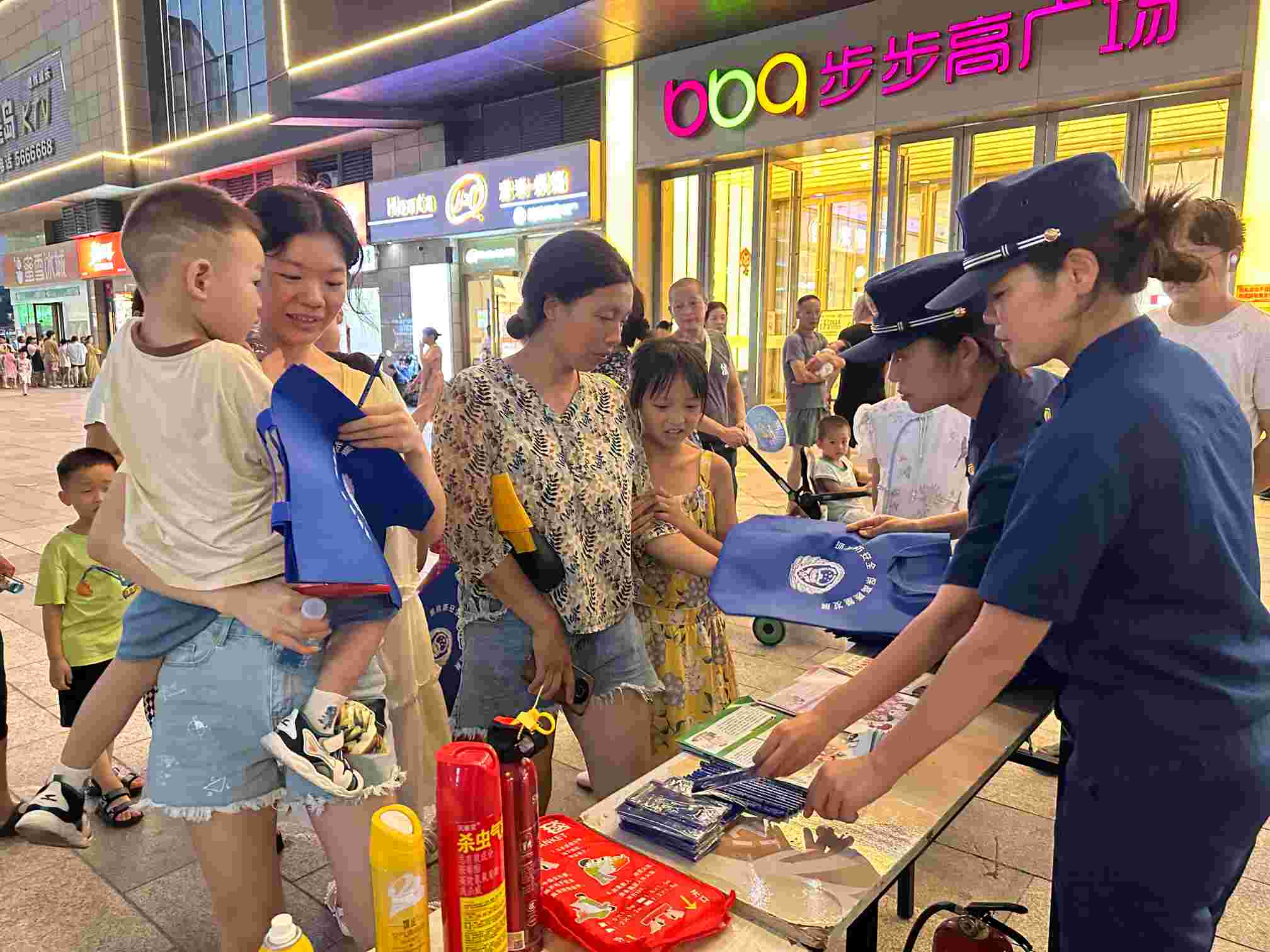 消防宣传员在摊位前向群众发放益阳消防文创产品（单位供图）