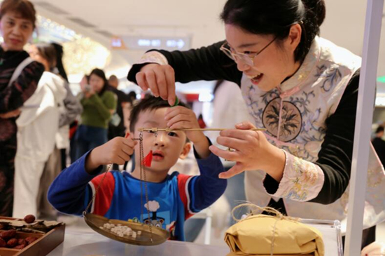 在中药中药展示专区，一位儿童正在体验中药调剂。袁利摄