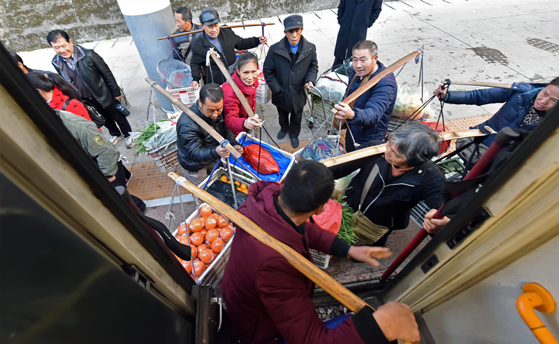 早上，当地村民挑着农产品在锦和站上车。胡盛平摄