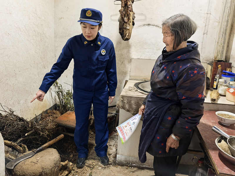 消防宣傳員提醒村民爐灶附近遠離易燃可燃物。（單位供圖）